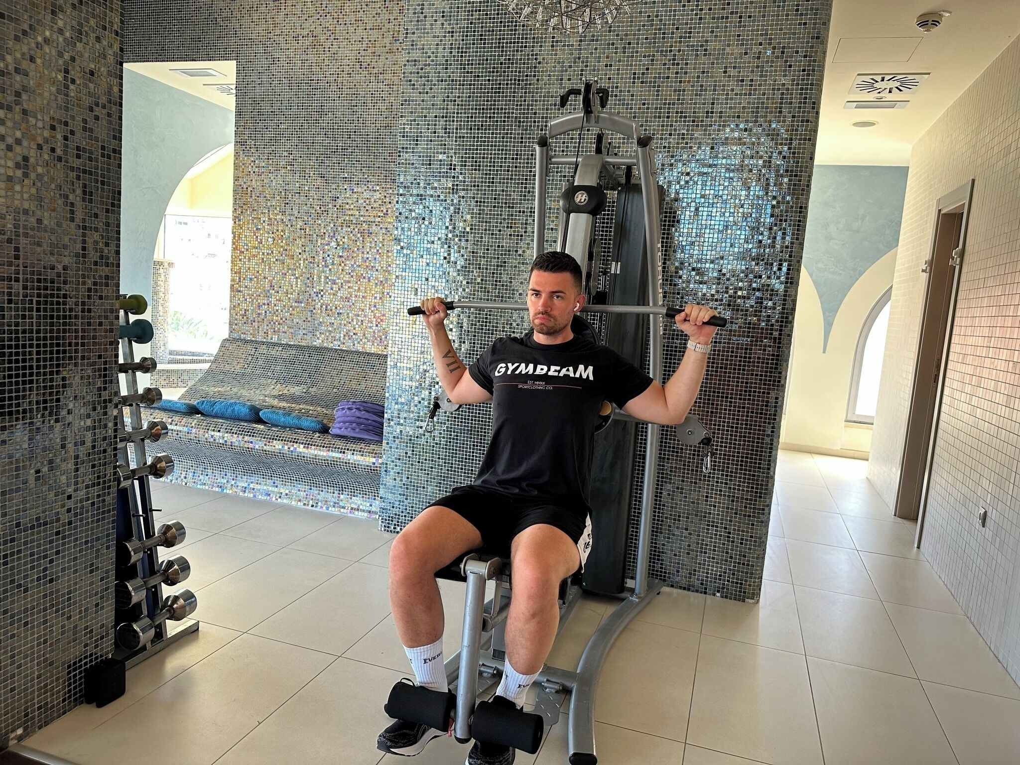 A gym with a mirrored wall, exercise equipment, and a bench.