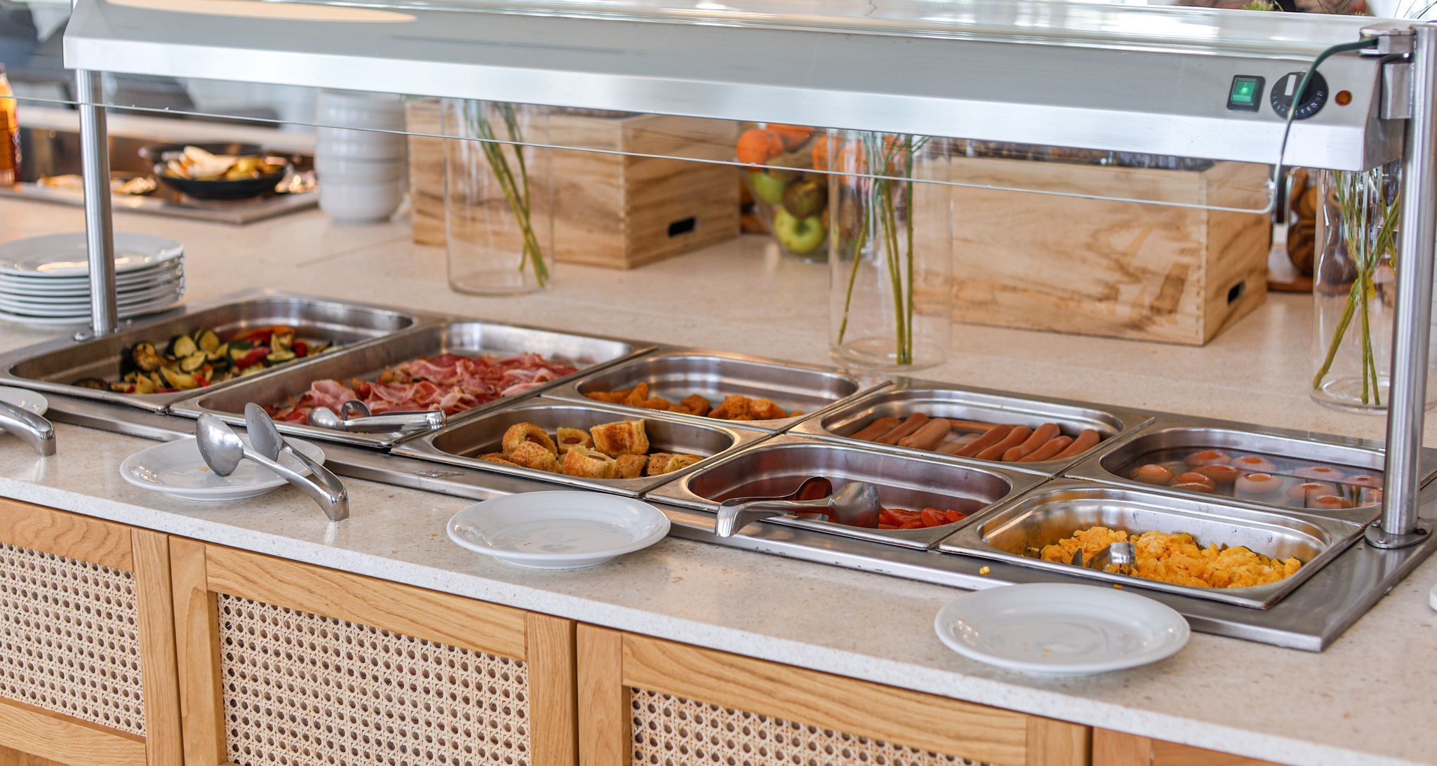 Ein Buffet mit verschiedenen Speisen, darunter Fleisch, Gemüse und Hot Dogs.