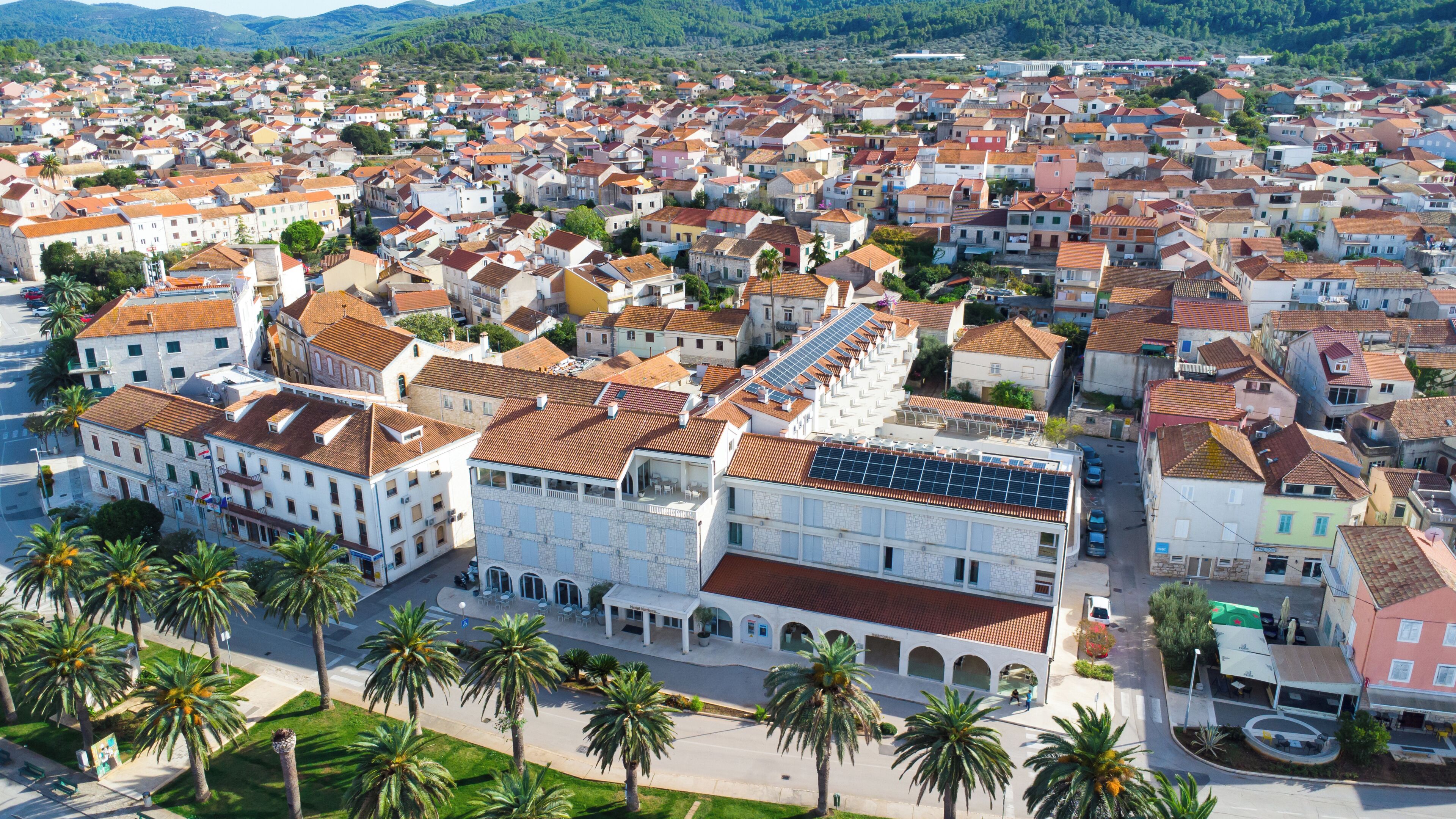 A coastal town with a mix of traditional and modern architecture, featuring a prominent building with a solar panel installation.