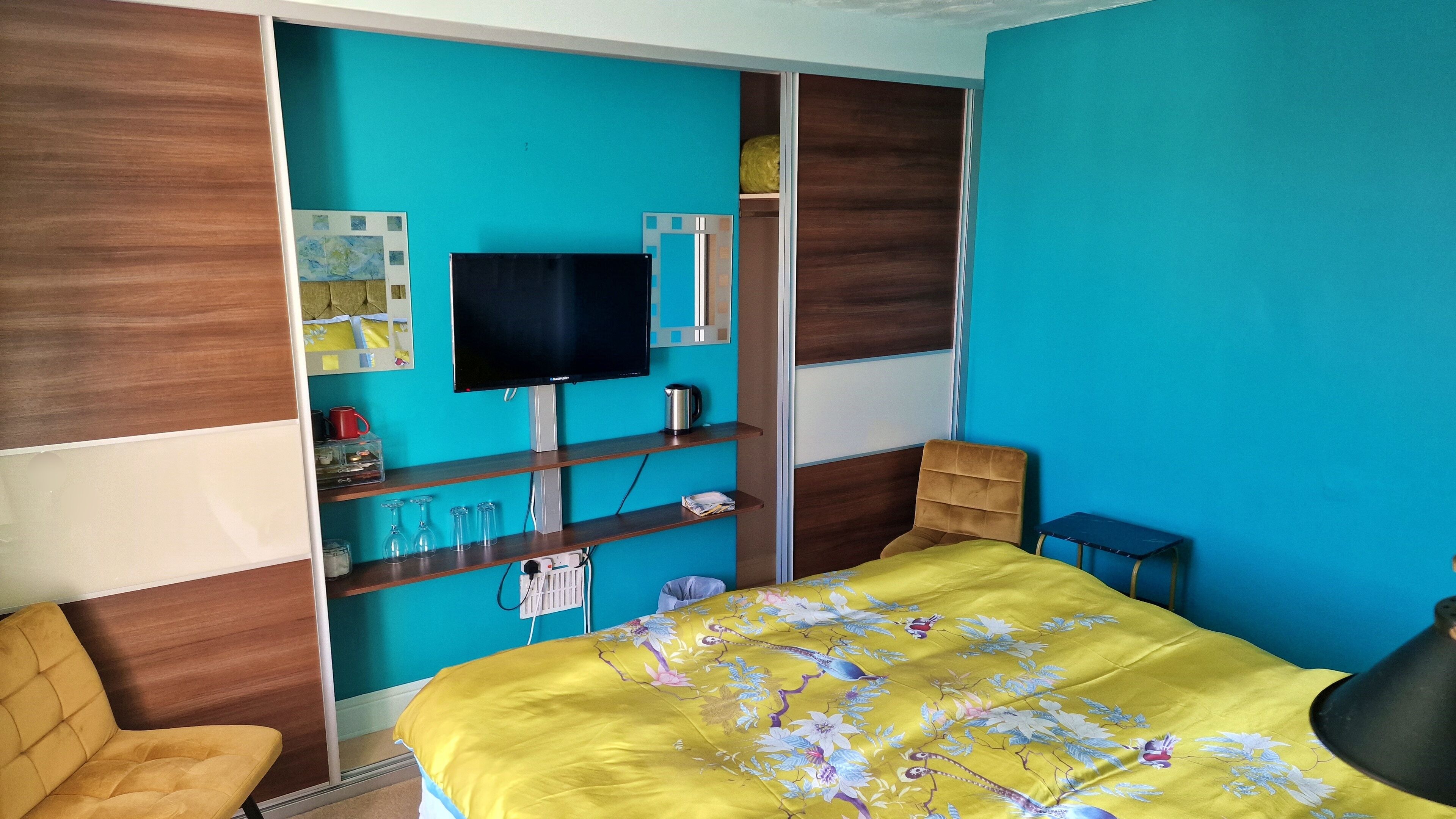 A bedroom with a bed, a TV, a chair, and a small table.