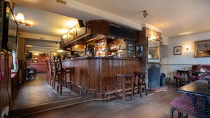 Un espace bar avec des tabourets en bois, un comptoir avec un tableau affichant le menu et un mur en briques.