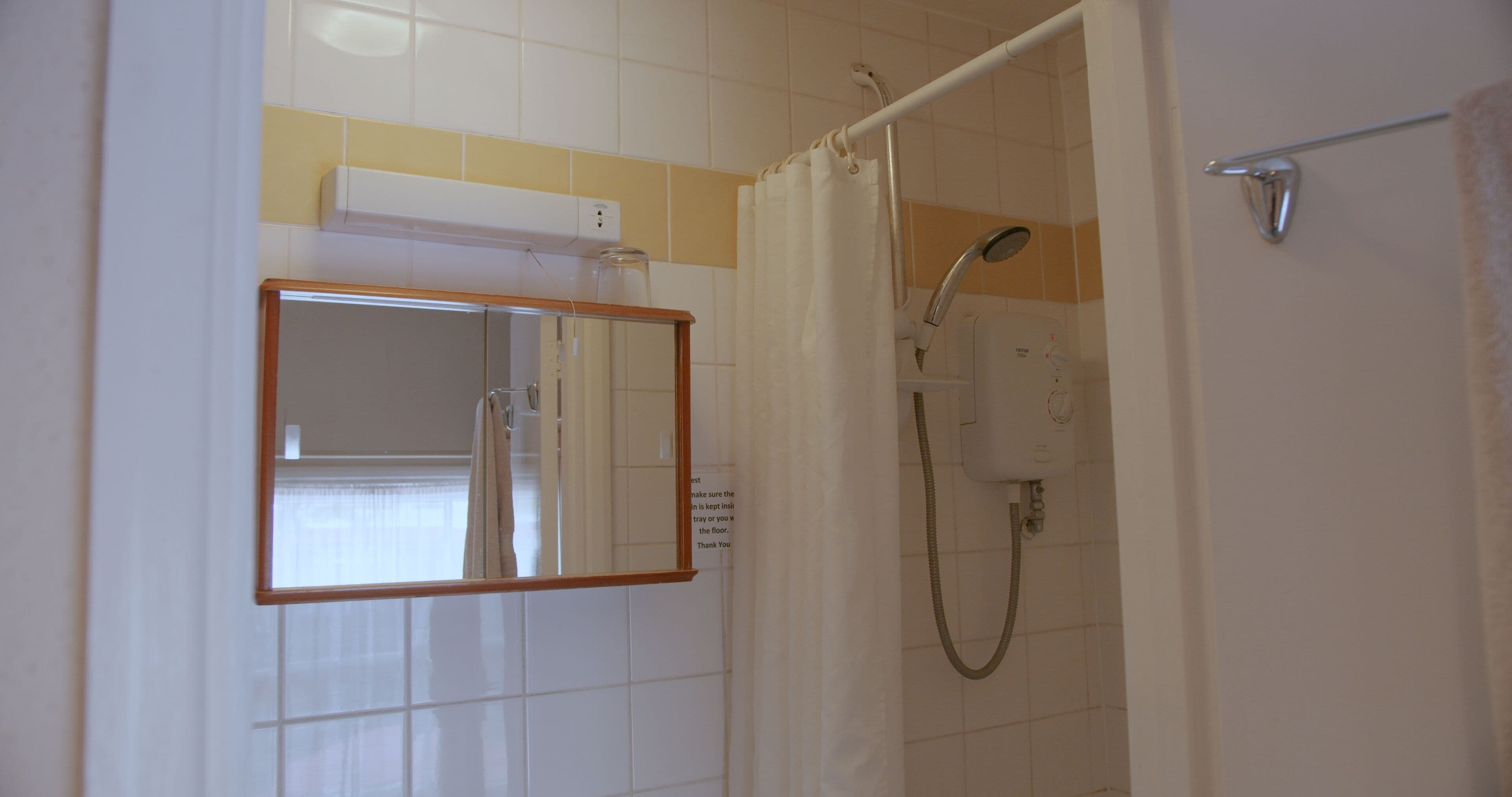 A bathroom with a shower, a mirror, and a towel rack.