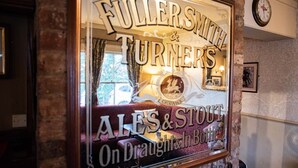 Une affiche à la fenêtre avec l’inscription : « FULLER’S, bières et stout TURNERS, disponibles à la pression et en bouteille ».