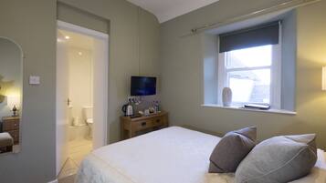 Un dormitorio con cama, mesita de noche, televisor y ventana con vistas.