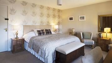 A neatly arranged bedroom with a large bed, bedside tables, a chair, a bench, and a mirror.
