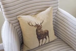 A chair with a striped fabric and a pillow featuring a deer silhouette.