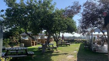 A garden area with picnic tables, wooden shelters, and a clear sky.