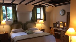 Une chambre à coucher avec un lit double, deux tables de chevet avec des lampes, une commode, un miroir et une horloge murale.