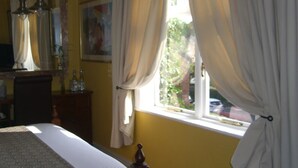 A bedroom with a bed, a nightstand, a mirror, and curtains. - Ash Farm Country Guest House (Altrincham)