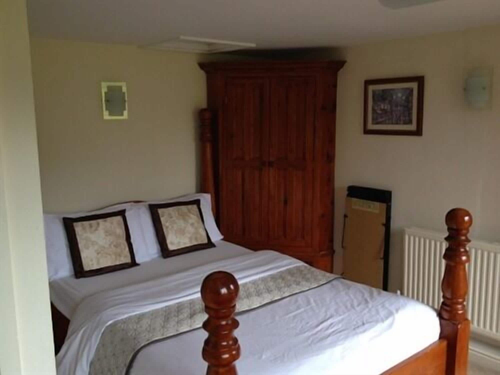 Une chambre à coucher avec un lit en bois, une grande armoire et un radiateur.