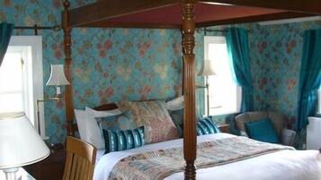Un lit à baldaquin avec une couvre-lit à motifs floraux, une tête de lit en bois et une fenêtre avec des rideaux.