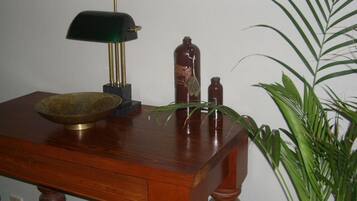 A wooden table with a green lamp, a brass bowl, and two bottles.