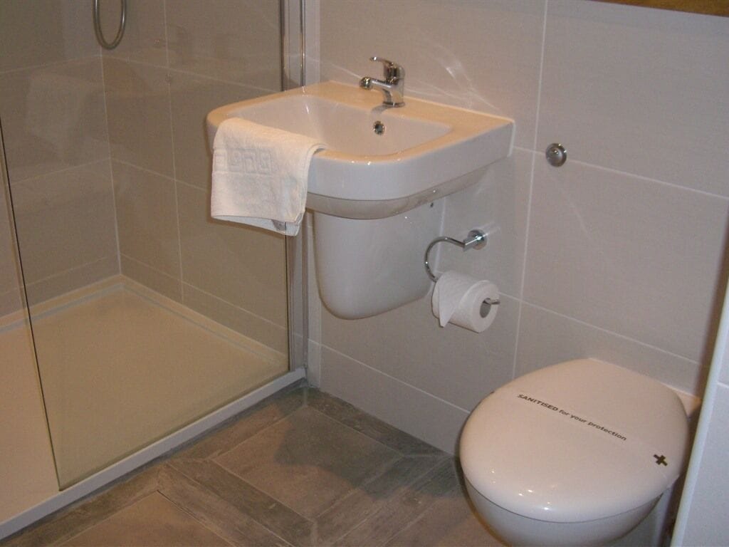 A bathroom with a white sink, toilet, and shower.