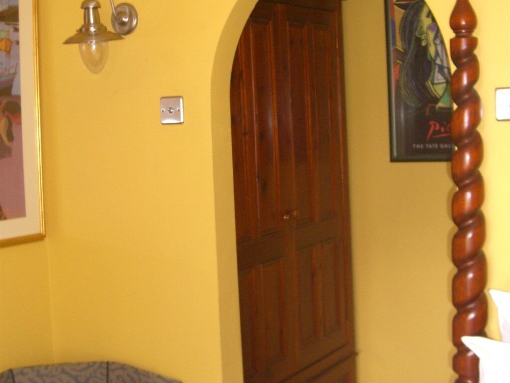 Ein Zimmer mit einem Holzschrank, einem Lichtschalter und einem Poster an der Wand.