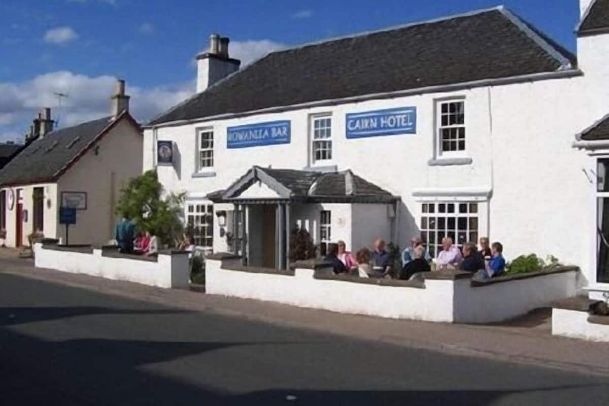 A white building with a sign reading "Cairn Hotel" and "Cornelia Bay."