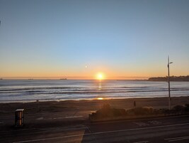 Una puesta de sol sobre una playa, con una carretera en primer plano.