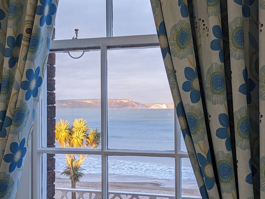 A window with a view of the sea and a mountain range.