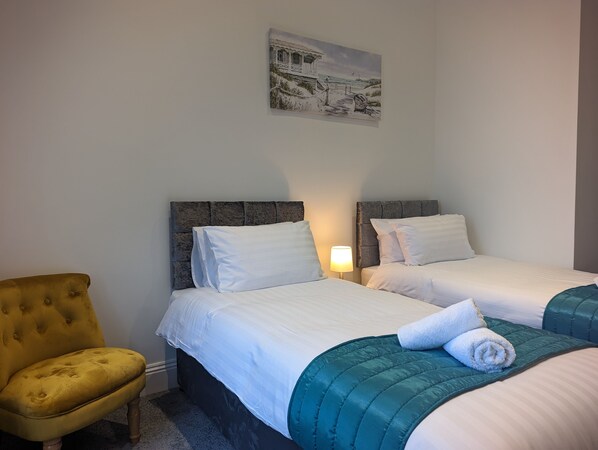 Una habitación de hotel con dos camas, una silla y un cuadro en la pared.