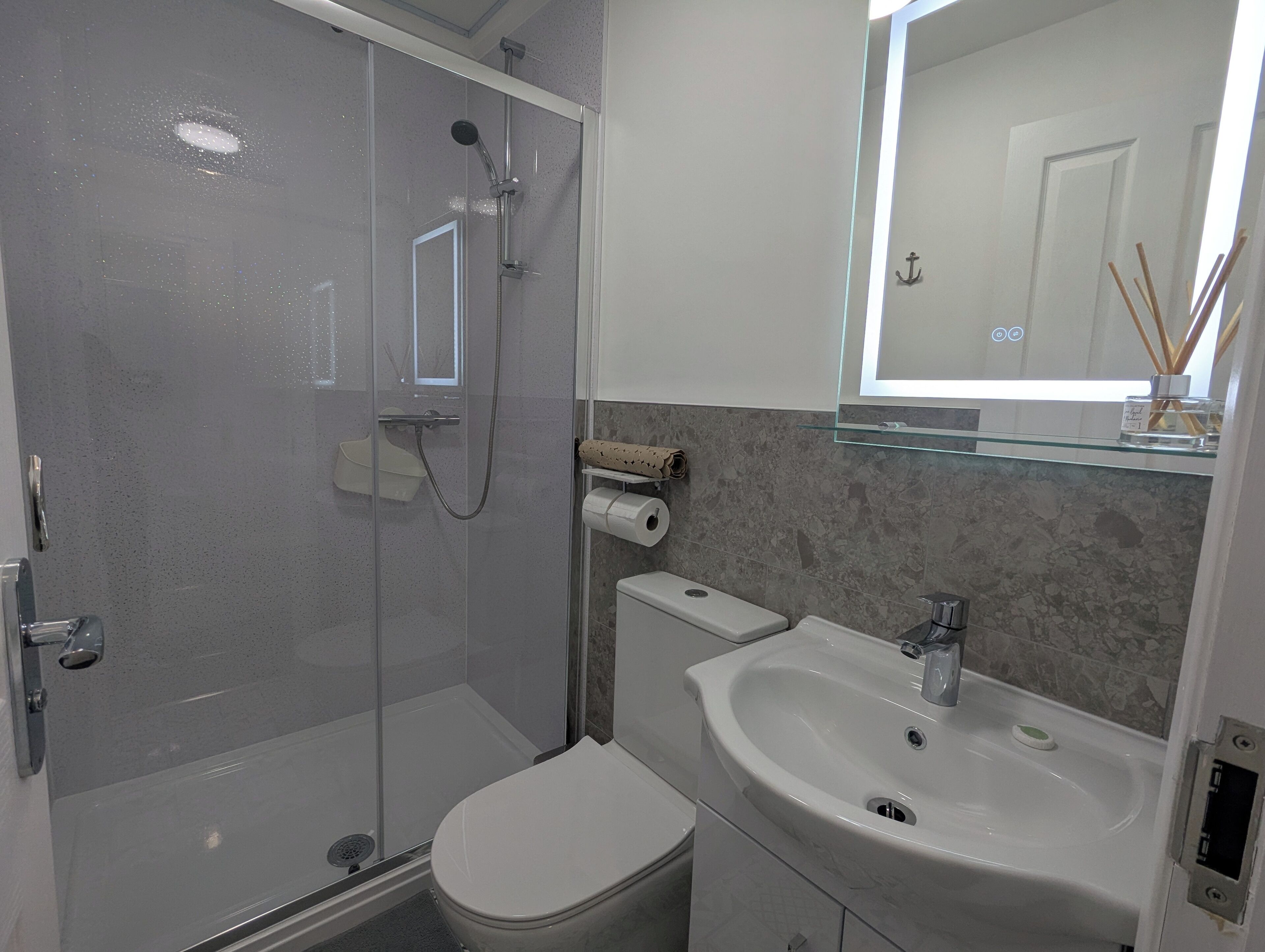 A bathroom with a glass-enclosed shower, a toilet, a sink, and a mirror.