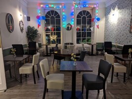 Un comedor con mesas y sillas, decorado con globos y luces de cadena.