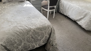 A bedroom with two beds, a desk, a chair, and a dresser. - Tower Hill Guest House (Basingstoke)