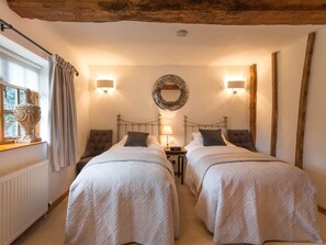 Un dormitorio acogedor con dos camas, techo de madera, un espejo y una ventana con cortinas.