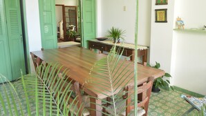 Un comedor con una mesa y sillas de madera, un ventilador de techo y una puerta verde.
