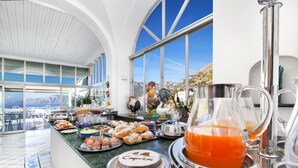 A breakfast buffet with various pastries, a cake, and a pitcher of orange juice. - Hotel Smeraldo (Praiano)