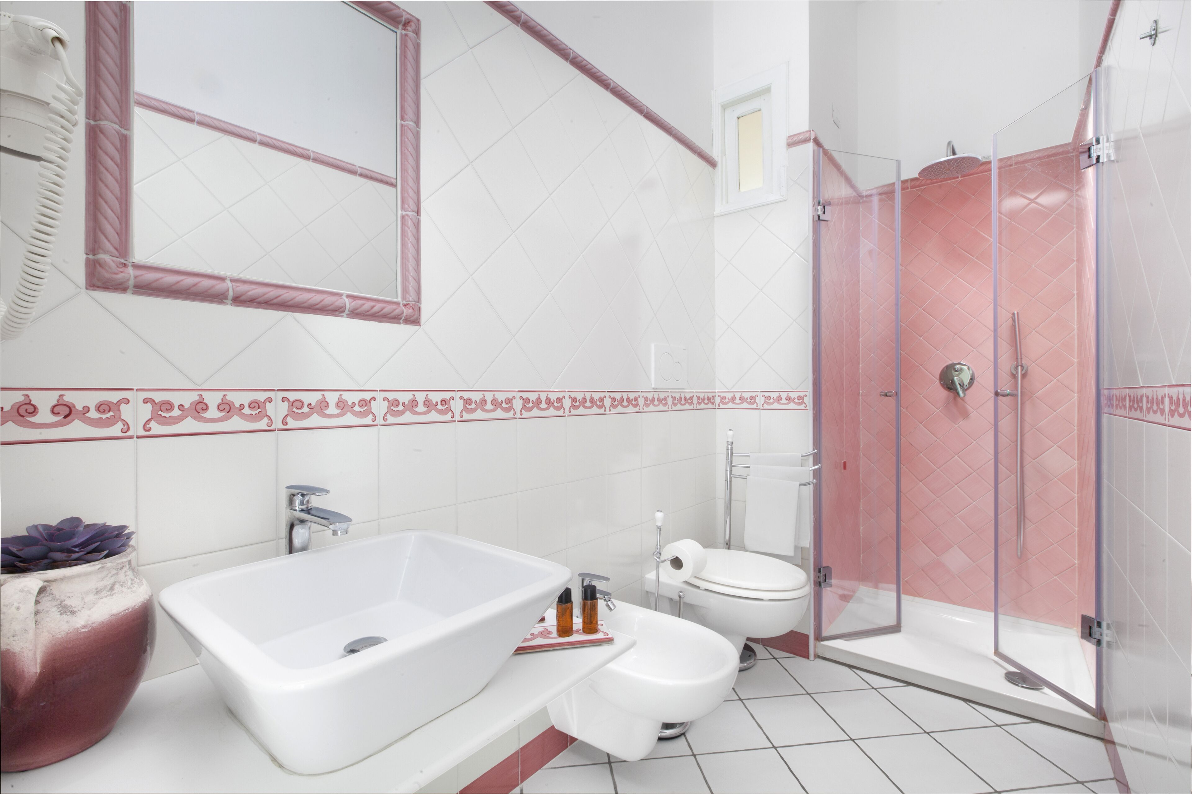 Un baño con una bañera blanca grande, un inodoro y una ducha con mampara de vidrio.
