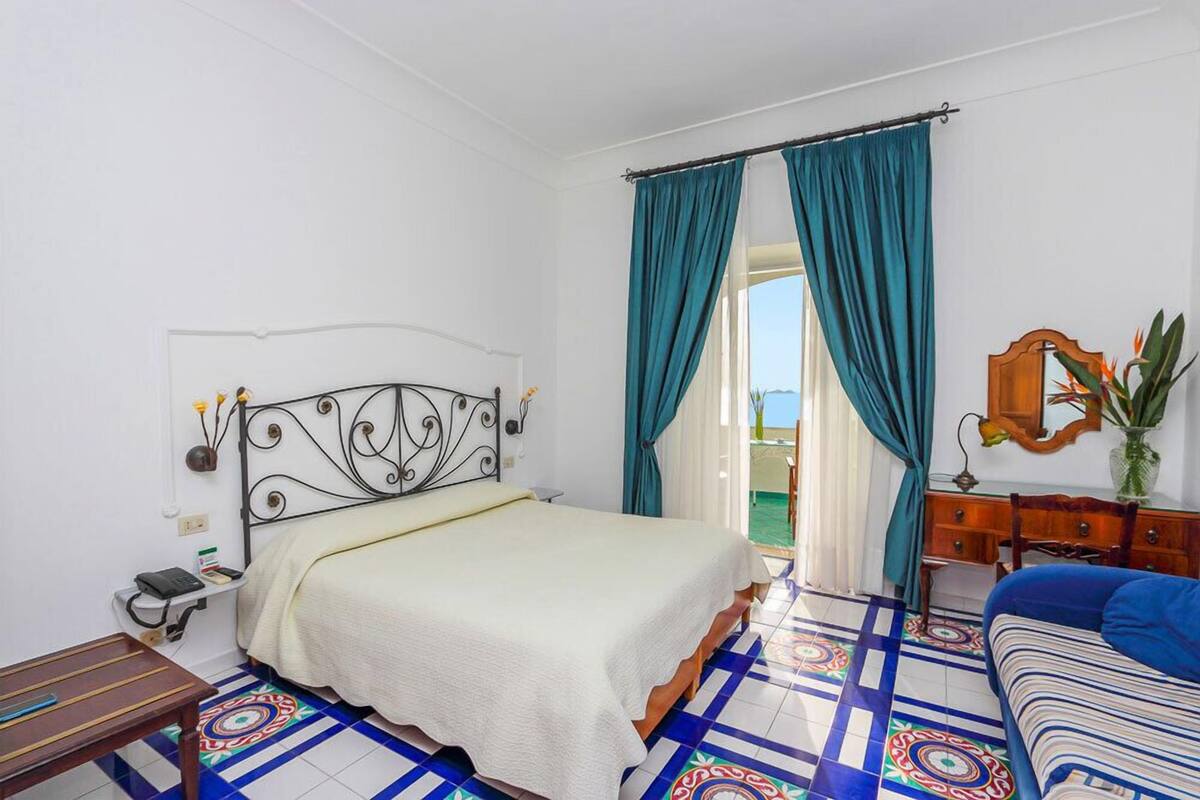 Un dormitorio con cama, mesita de noche, cómoda y vistas al exterior.