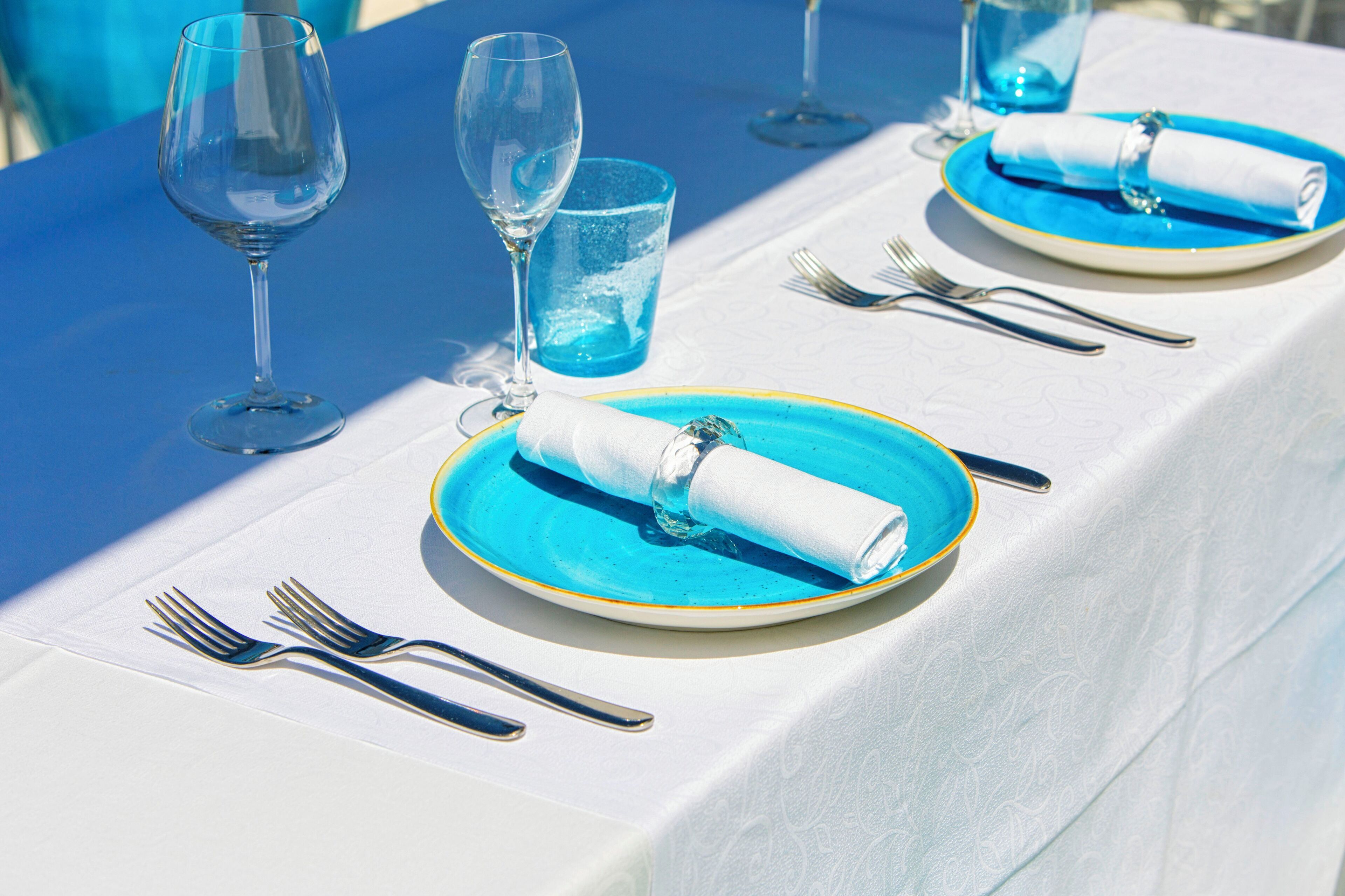 A table set with a blue and white tablecloth, clear glassware, and neatly folded napkins.