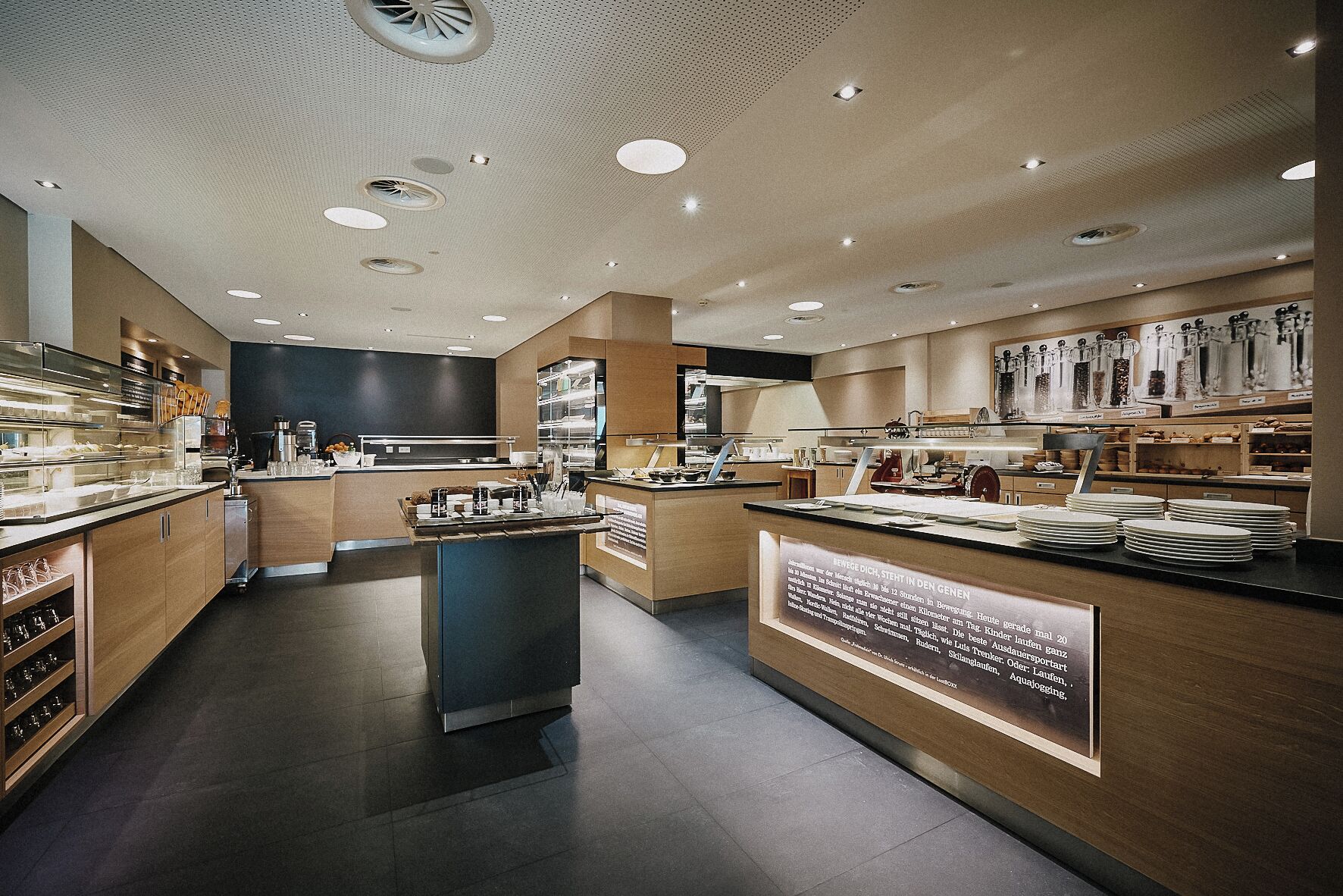 En modern restaurang med en central bardisk, flera olika typer av sittplatser och ett varierat utbud av matpresentationer.