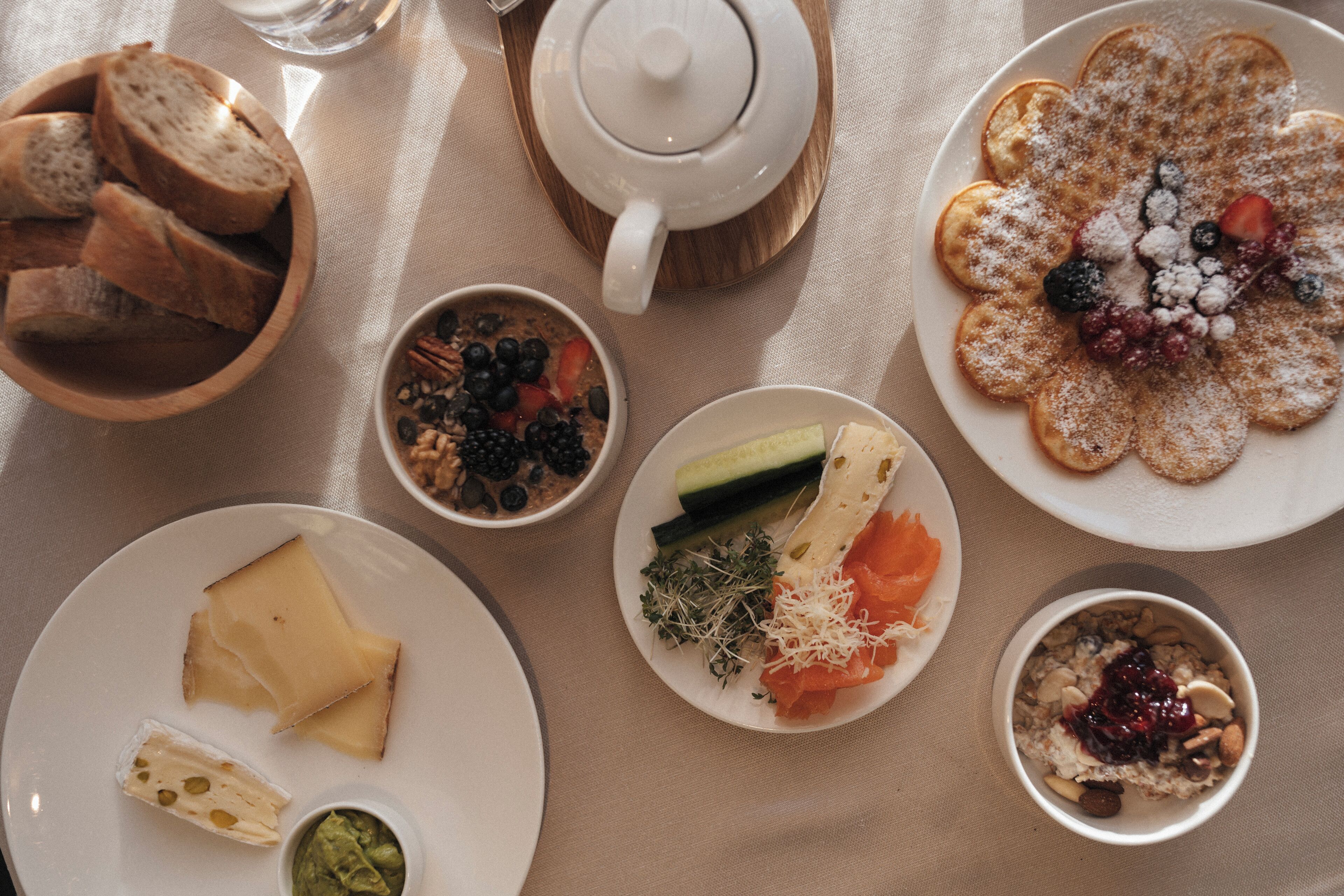 A table with various food items including bread, cheese, and a variety of fruits and vegetables.