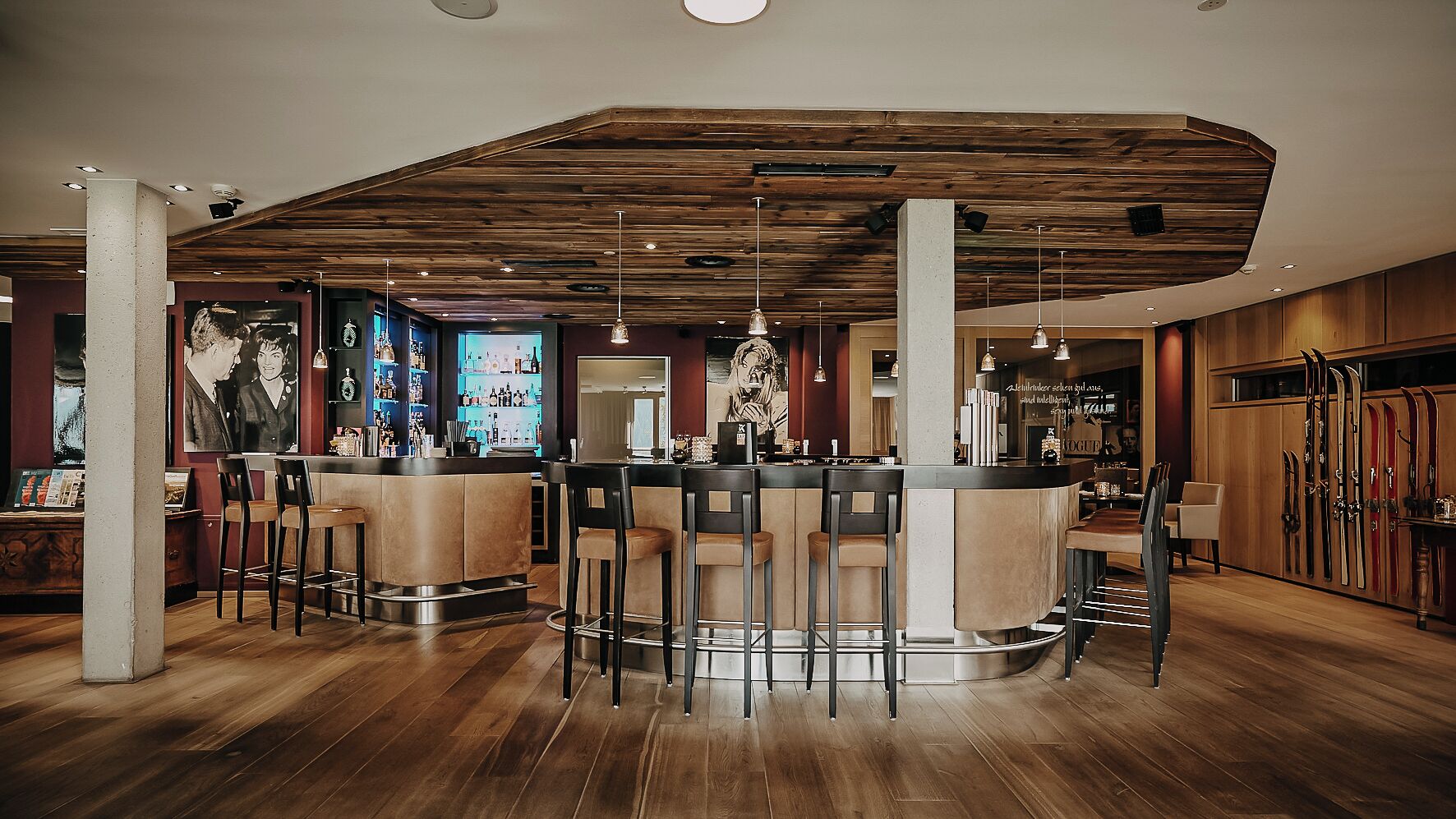Un área de bar moderna con suelo de madera, taburetes y un techo alto con vigas a la vista.