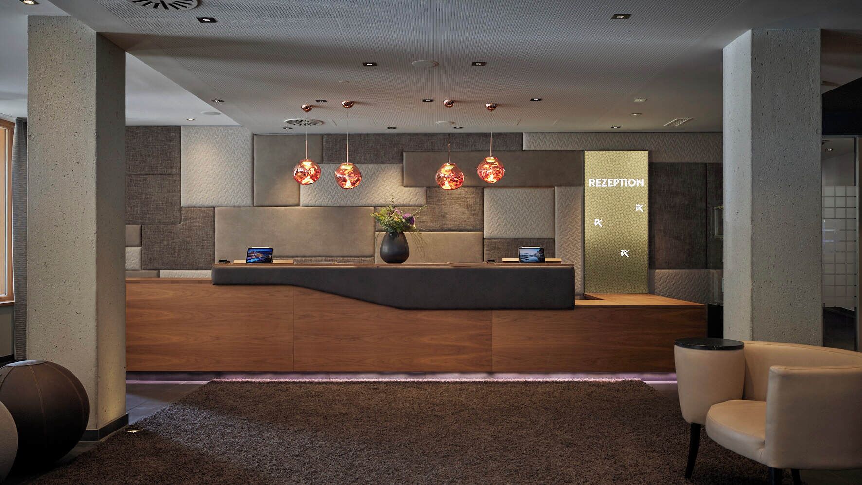 A reception area with a modern design, featuring a curved reception desk, pendant lighting, and a reception desk with a digital display.