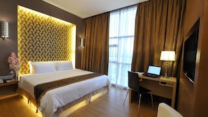 Une chambre d’hôtel avec un grand lit, un bureau avec un ordinateur portable, une télévision et une chaise.
