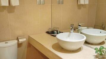 A bathroom with two sinks, a toilet, and a mirror.