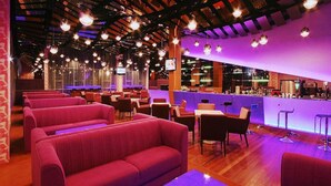 Un restaurant avec des banquettes rouges, un bar et des lampes suspendues.