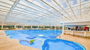 Una piscina interior con techo de cristal, varias pistas de natación y zona de bar.