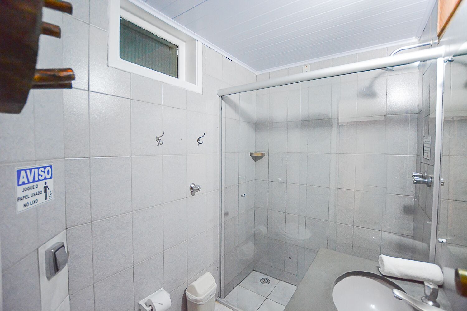 Casa de banho pequena e moderna, com chuveiro, sanita e lavatório.