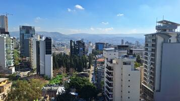 A cityscape with modern high-rise buildings, a clear sky, and distant mountains.