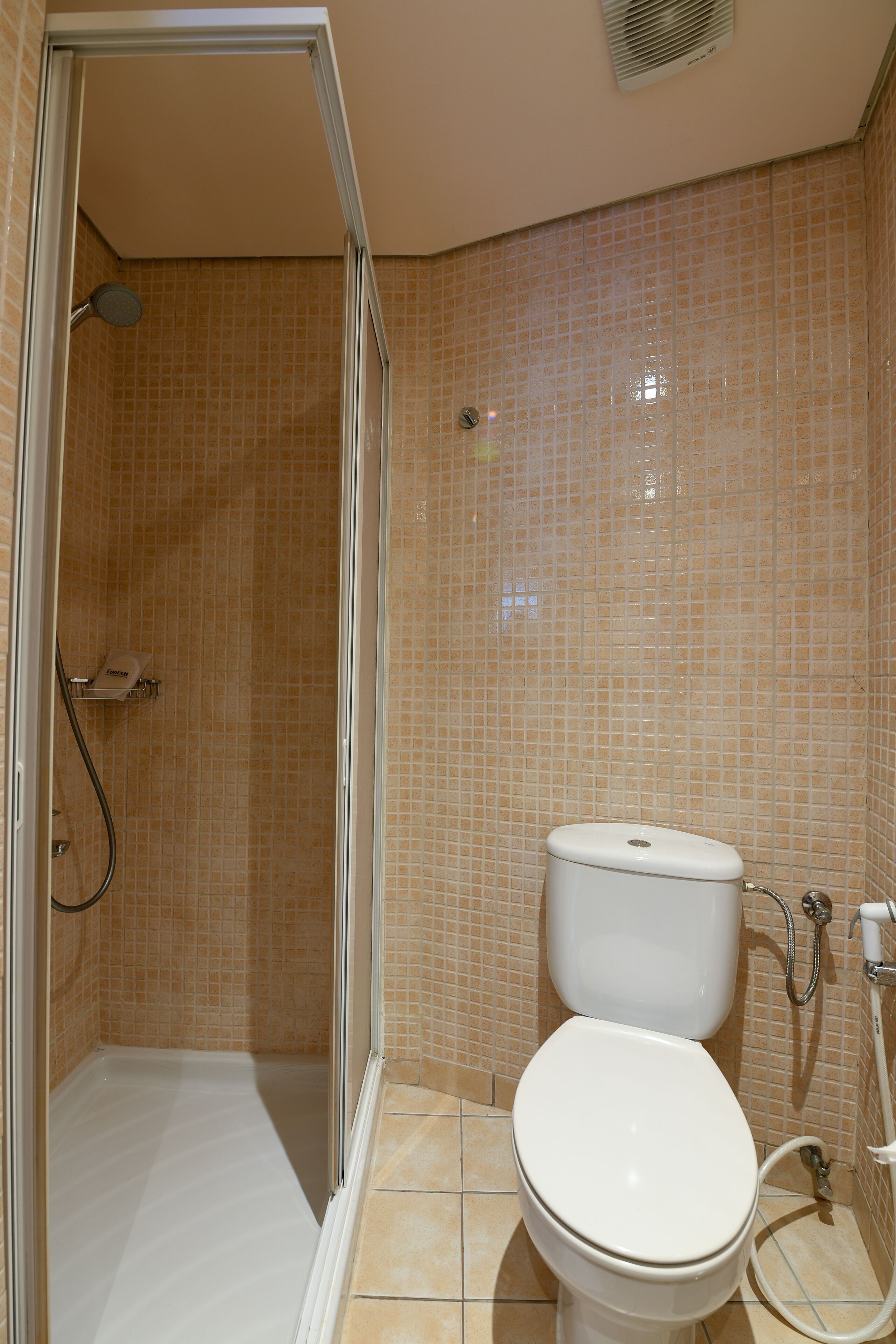 Un baño con ducha, inodoro y paredes de azulejos.