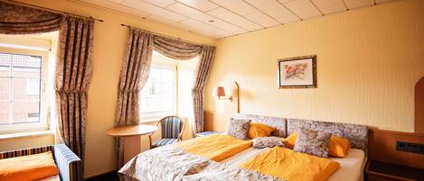 Una habitación de hotel con una cama, una silla, una mesita y una lámpara.