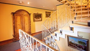 A grand staircase with ornate metal railings and a wooden door at the bottom. - Hotel Heideparadies (Soltau)