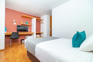 Un dormitorio con cama, escritorio, silla, televisor y armario.