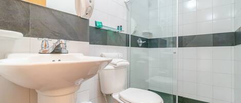 A modern bathroom with a white sink, toilet, and glass shower enclosure.