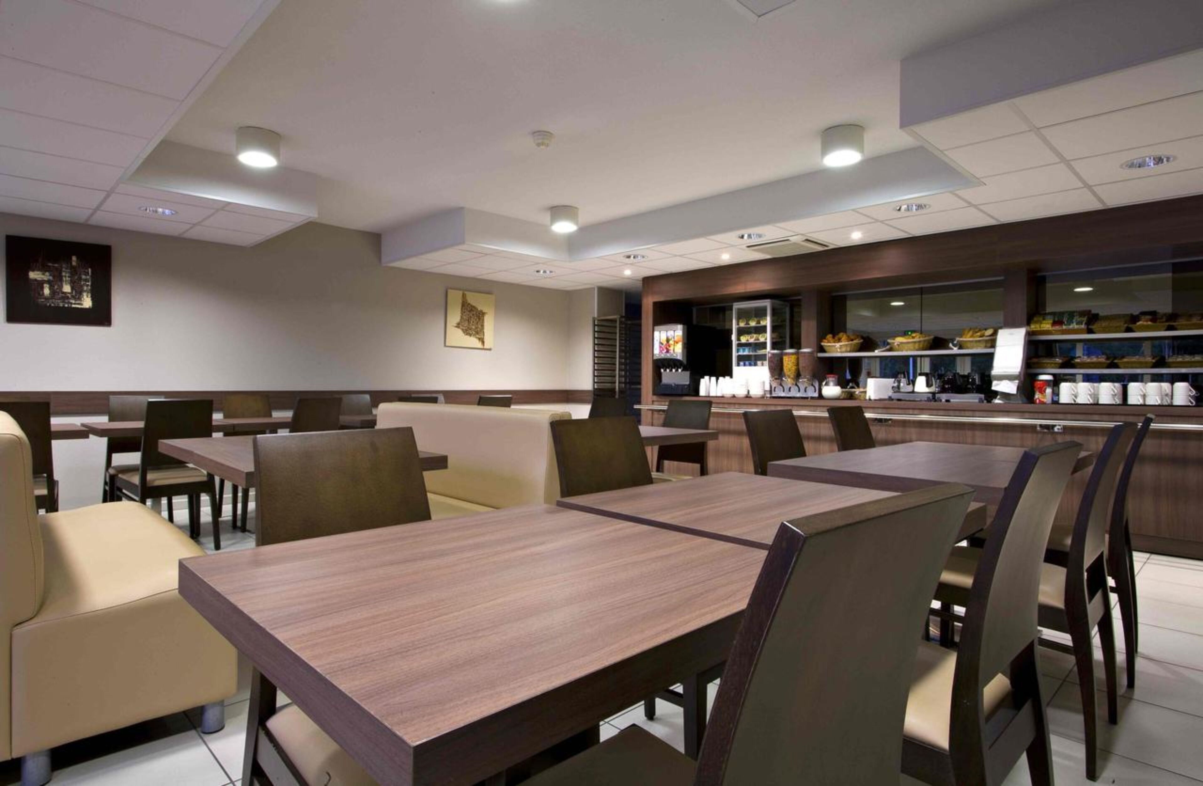 A restaurant with booths and tables, a counter with food and drinks, and a cityscape view.
