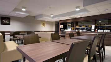 Ein Restaurant mit Sitzgelegenheiten in Form von Boxen und Tischen, einer Theke mit Speisen und Getränken sowie Blick auf die Stadt.