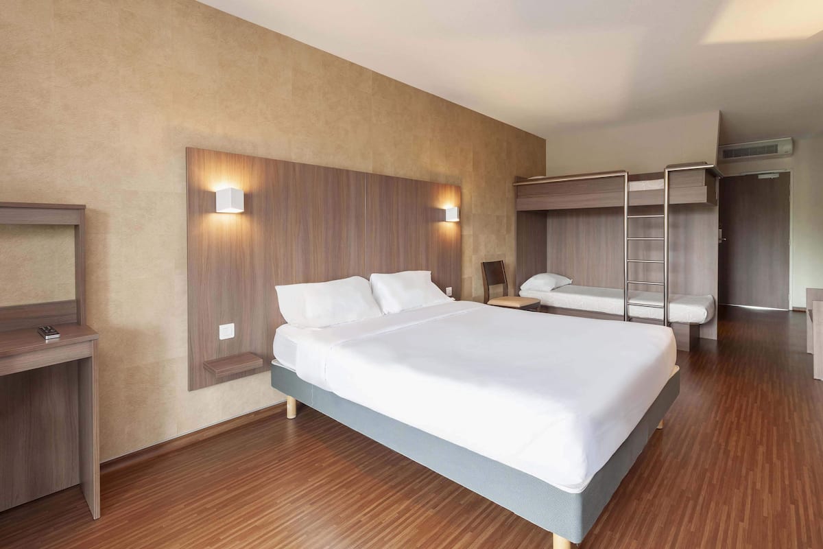 Ett modernt hotellrum med en stor säng, ett skrivbord, en garderob och en väggmonterad lampa.