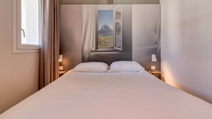A hotel room with a large bed, a window with curtains, and a view of mountains through the window. - B&B HOTEL Saint-Jean de Luz (Saint-Jean-de-Luz)